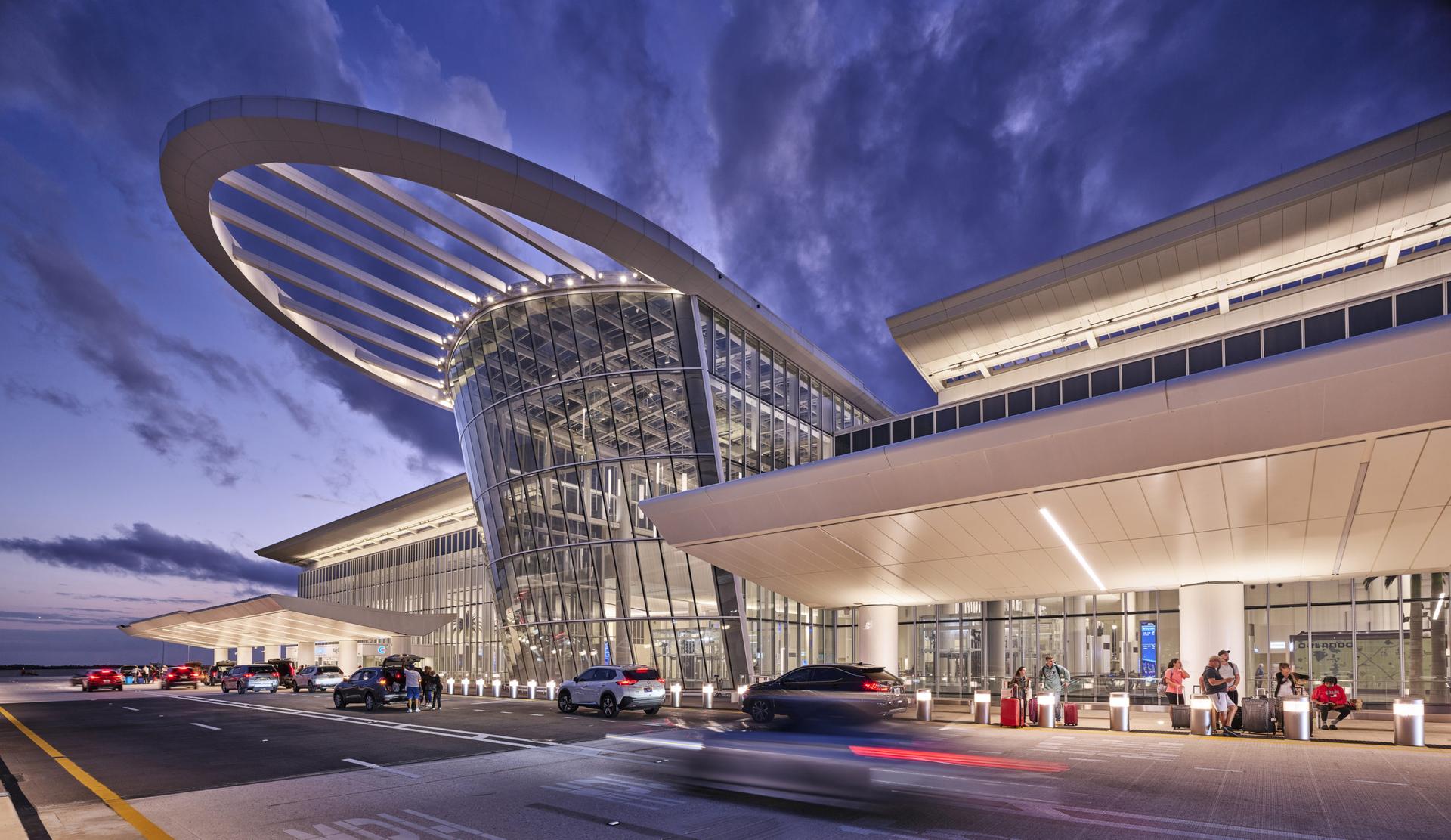 a building with a curved roof and cars parked on the side of the road